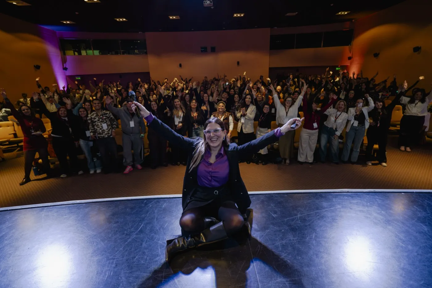 Romina Fuentes hablando sobre el escenario con luz violeta